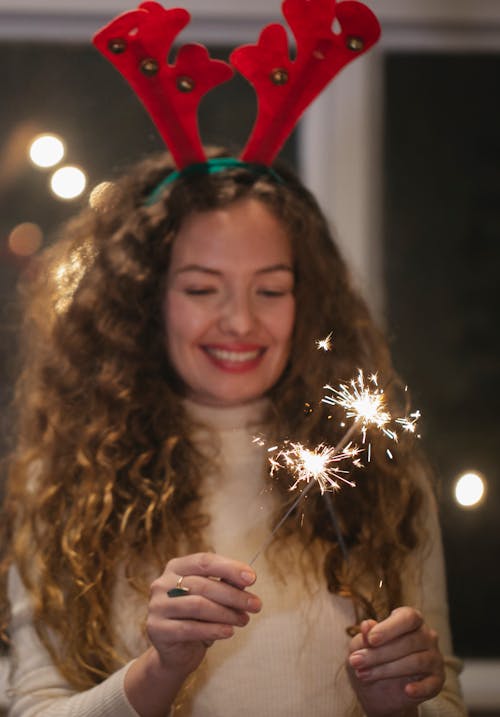 Happy woman with burning Bengal lights celebrating Christmas holiday