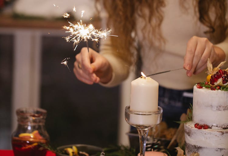 Crop Woman With Burning Sparkler Lighting Candle At Home