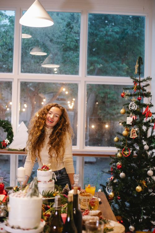Free Content female looking at camera at table with assorted treats for New Year holiday at home Stock Photo