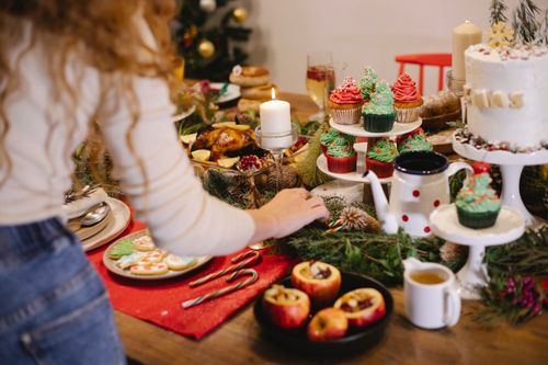 Free Back view of crop anonymous female preparing filled apples in baking dish on table with different desserts for New Year holiday Stock Photo