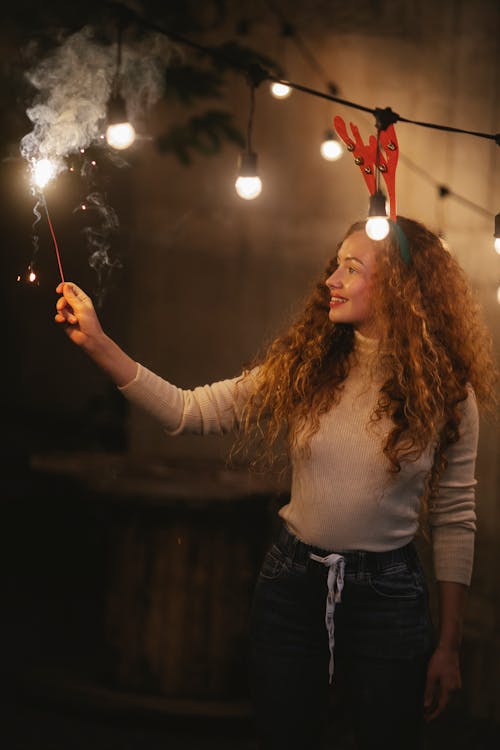 Candid woman with burning sparkler celebrating Christmas night