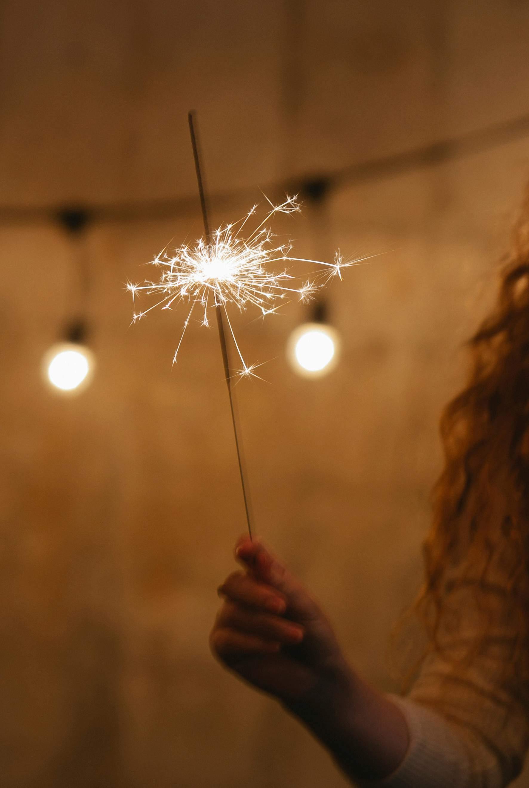 crop woman with luminous sparkler in twilight