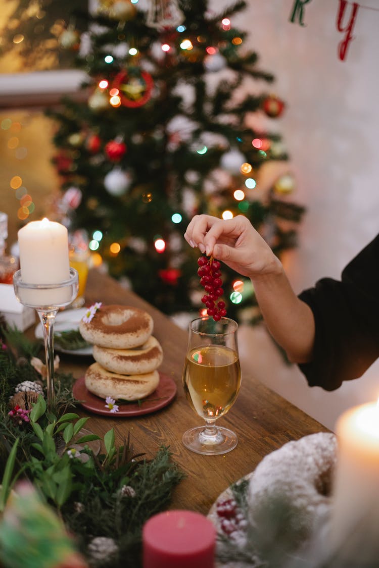 Crop Woman With Red Currants And Champagne On Christmas Day