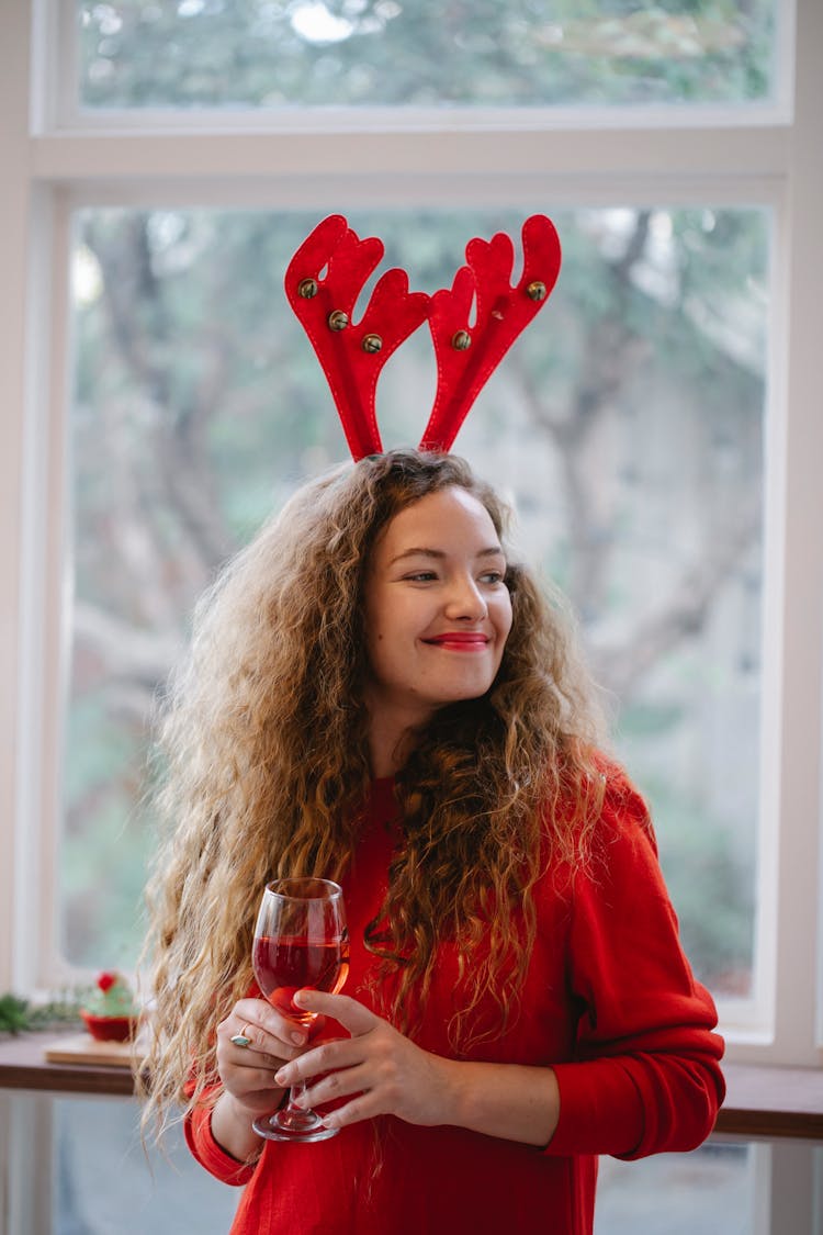 Glad Woman With Glass Of Wine During Christmas Holiday Indoors