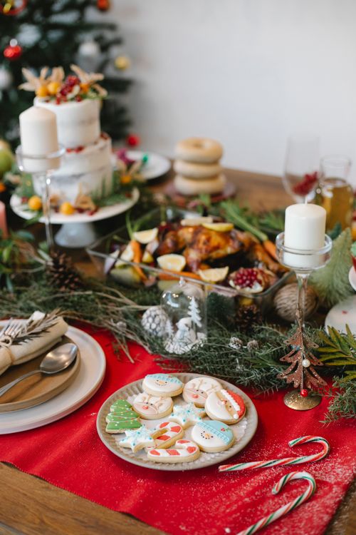 Free High angle of cake gingerbread placed near fried chicken on table decorated with candles and fir branches for Christmas celebration Stock Photo