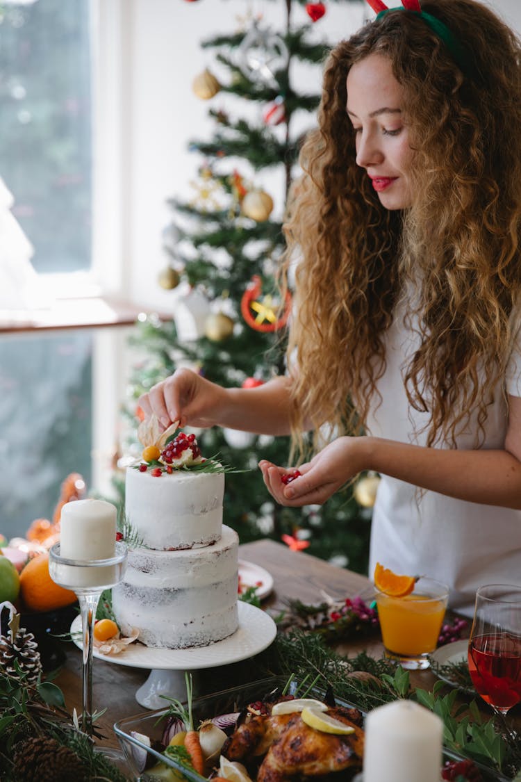 Woman Adding Berries On Top Of Two Tier Cake