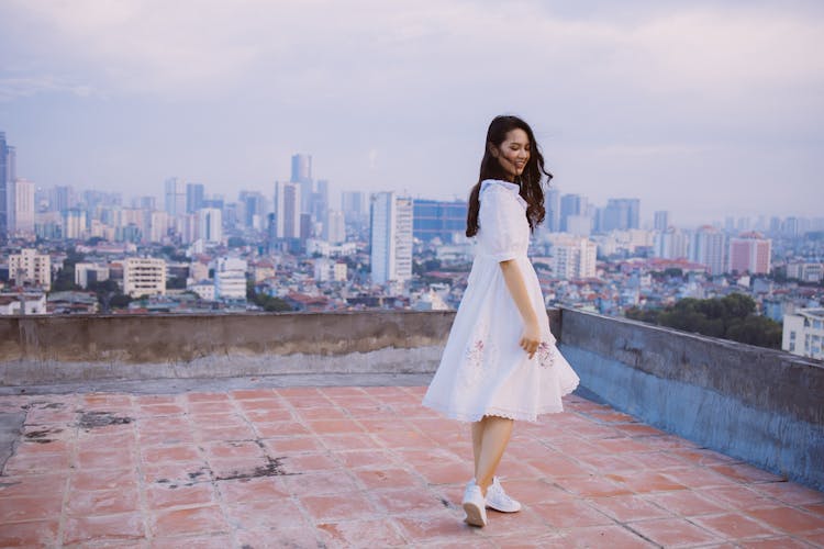 A Woman On The Rooftop Overlooking The Scenic City Buildings