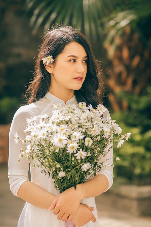 Free A Beautiful Woman Holding a Bunch of Daisies Stock Photo