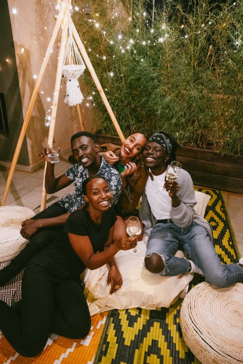 Free A group of friends relaxed and cheerful, enjoying a cozy evening indoors with drinks and fun. Stock Photo