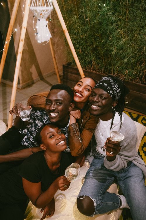 Free Four friends enjoying each other's company with smiles and drinks indoors, celebrating friendship. Stock Photo