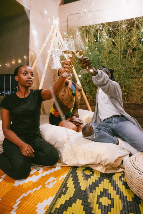 Free Three friends enjoying a cozy indoor gathering, toasting with wine glasses. Stock Photo