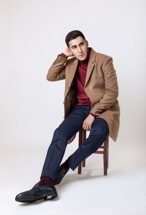 Free Elegant man in coat posing on chair in studio with white background. Stock Photo