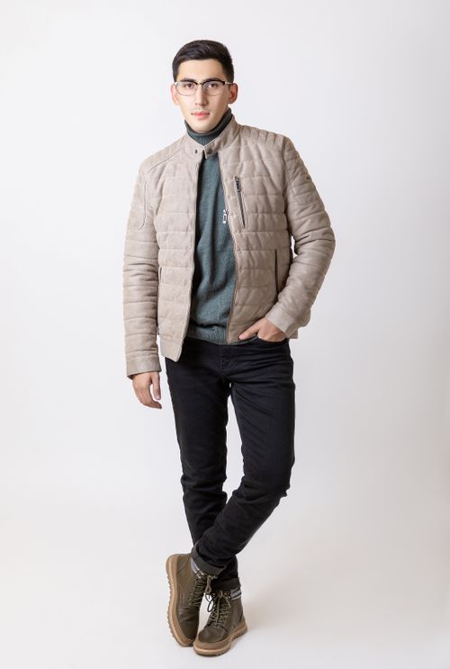 Free Fashionable young man wearing a beige jacket and eyeglasses, posing against a white background. Stock Photo