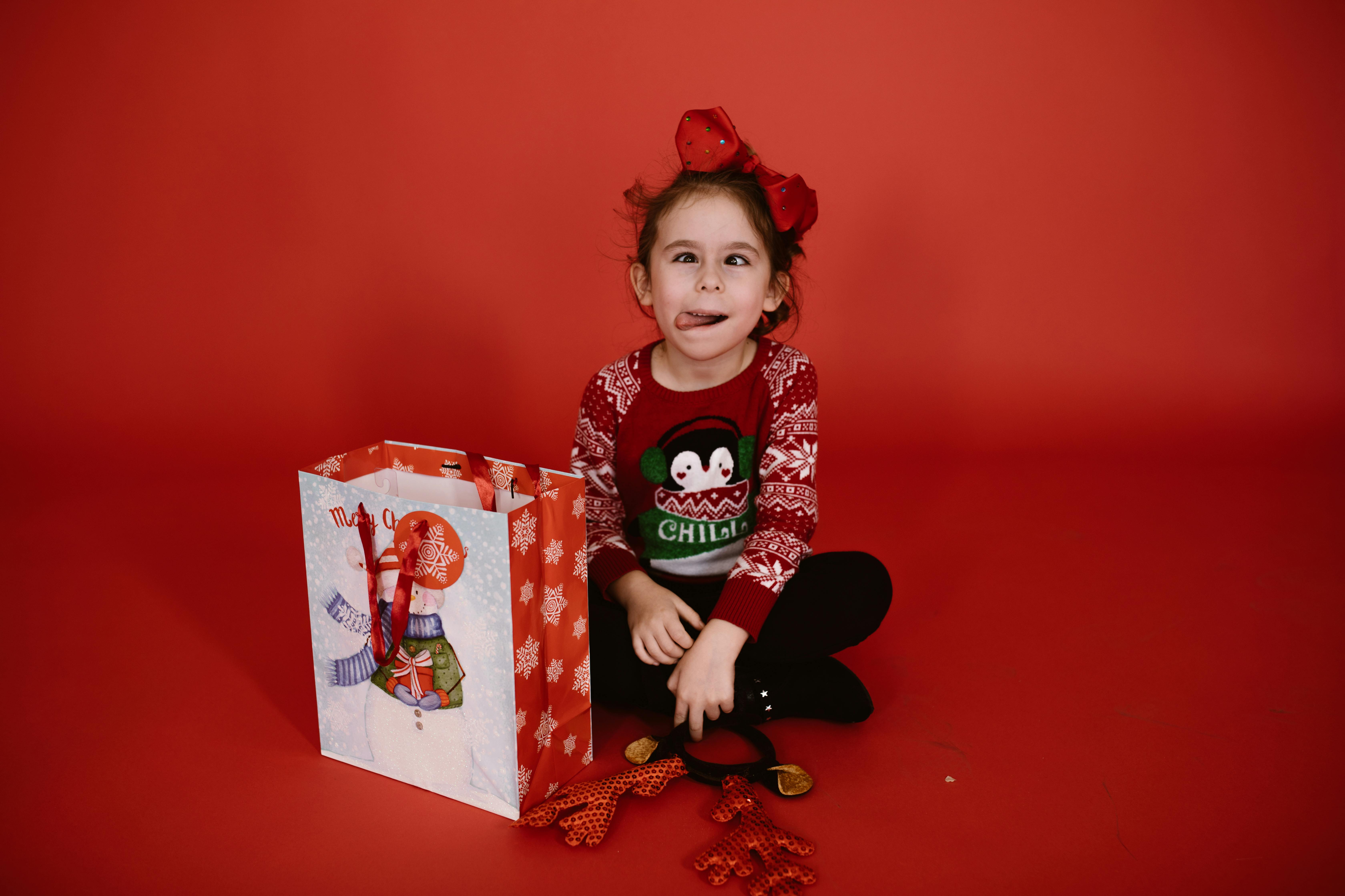 girl in black and white long sleeve shirt holding red and white gift box