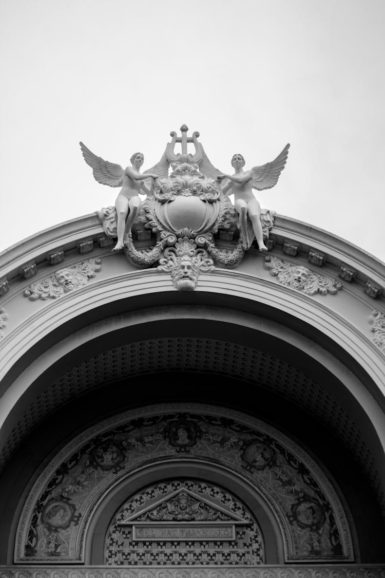 Grayscale Shot Of Angel Statues On An Arch