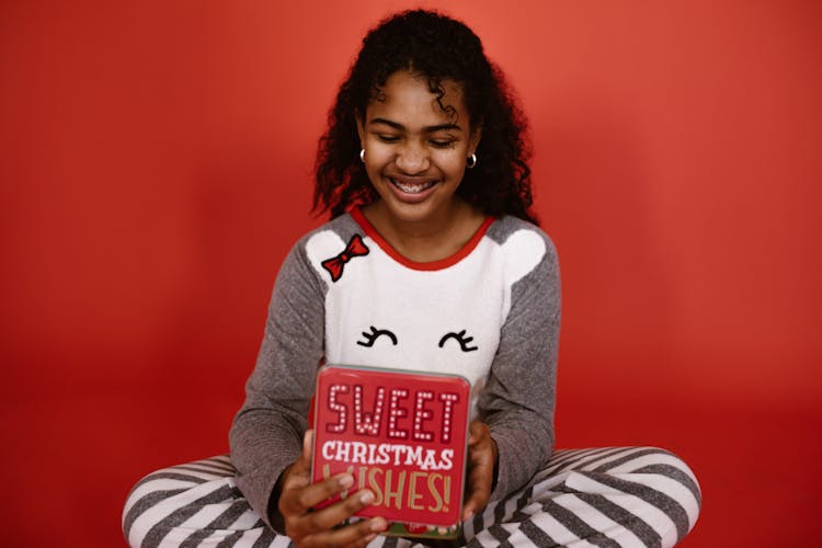 A Girl Smiling While Holding A Red Box