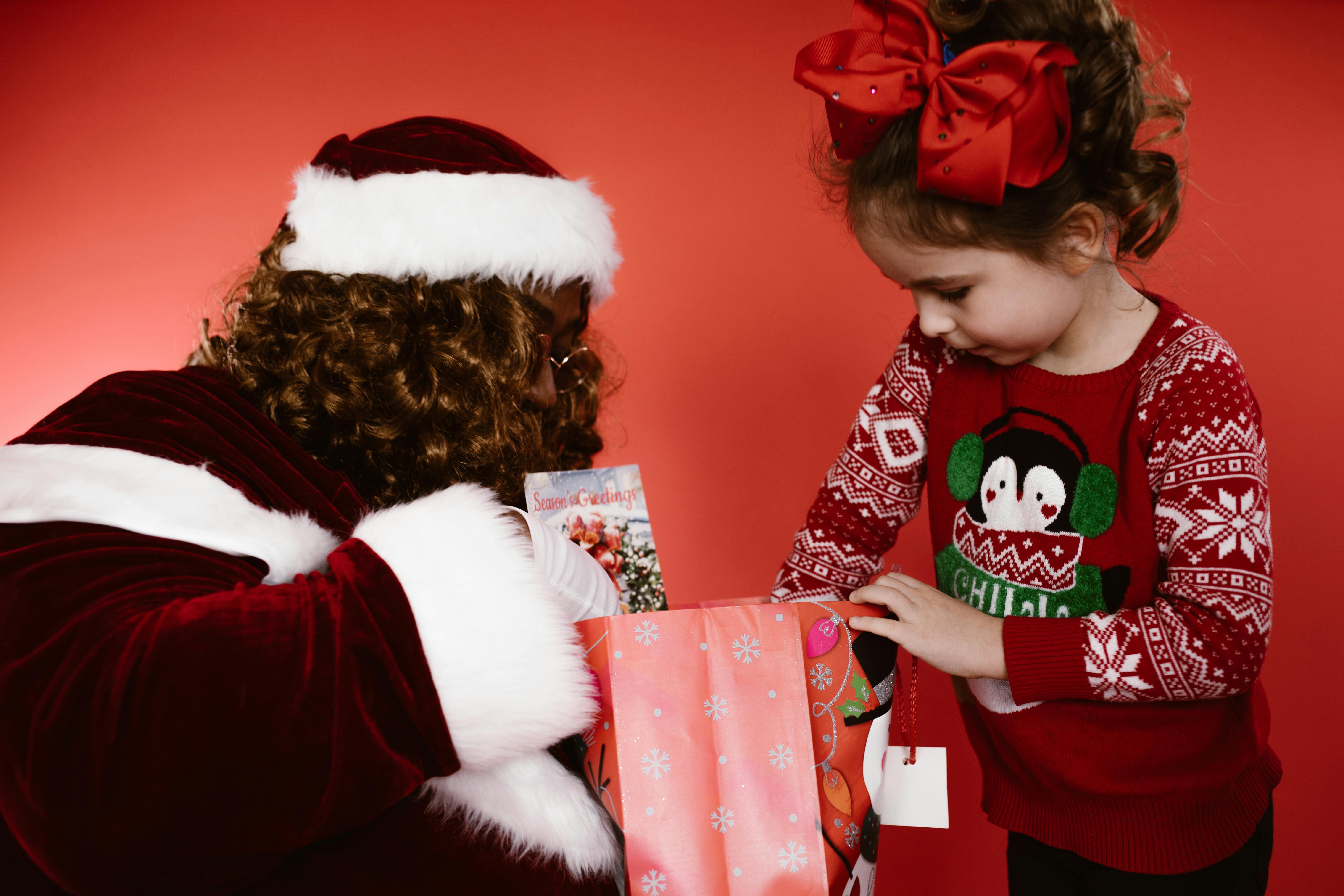 girl in red and white santa hat holding red gift box