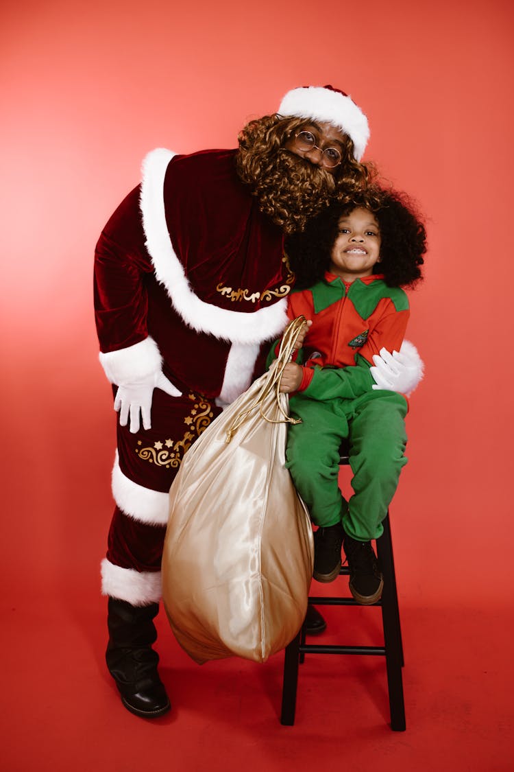 A Man In A Santa Costume And A Child In An Elf Costume