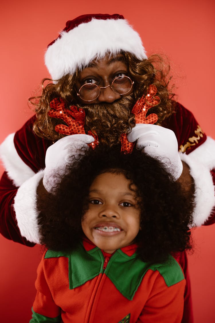 A Man In A Santa Costume And A Child In An Elf Costume