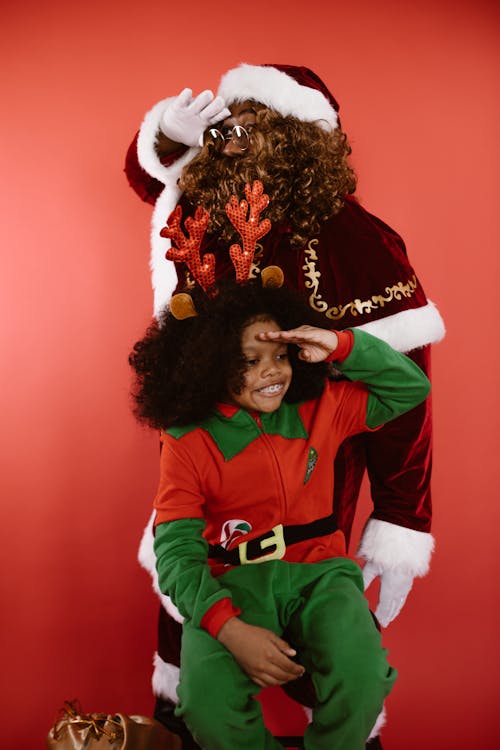 A Man and a Child in Santa Claus and Elf Costumes
