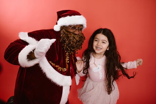 A Man in a Santa Costume and a Little Girl Dancing Together