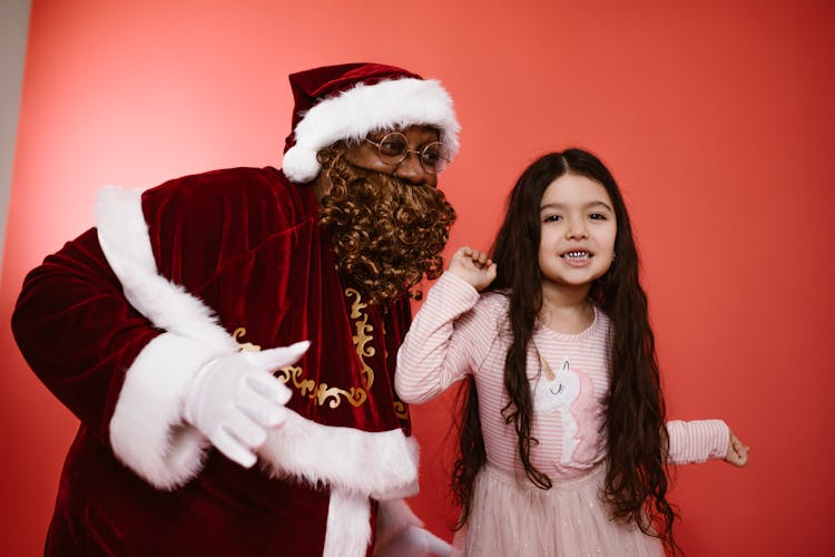 A Man In A Santa Costume And A Little Girl Dancing Together