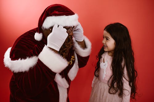 A Man in Santa Claus Costume Beside a Girl

