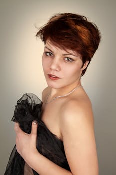 Artistic portrait of a woman in a black dress with short red hair, captured in a studio setting.