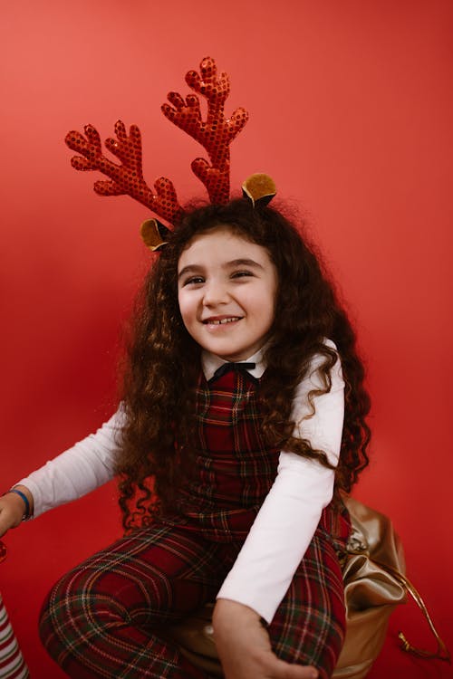 A Girl in Red Plaid Outfit Wearing Headband while Smiling at the Camera ·  Free Stock Photo