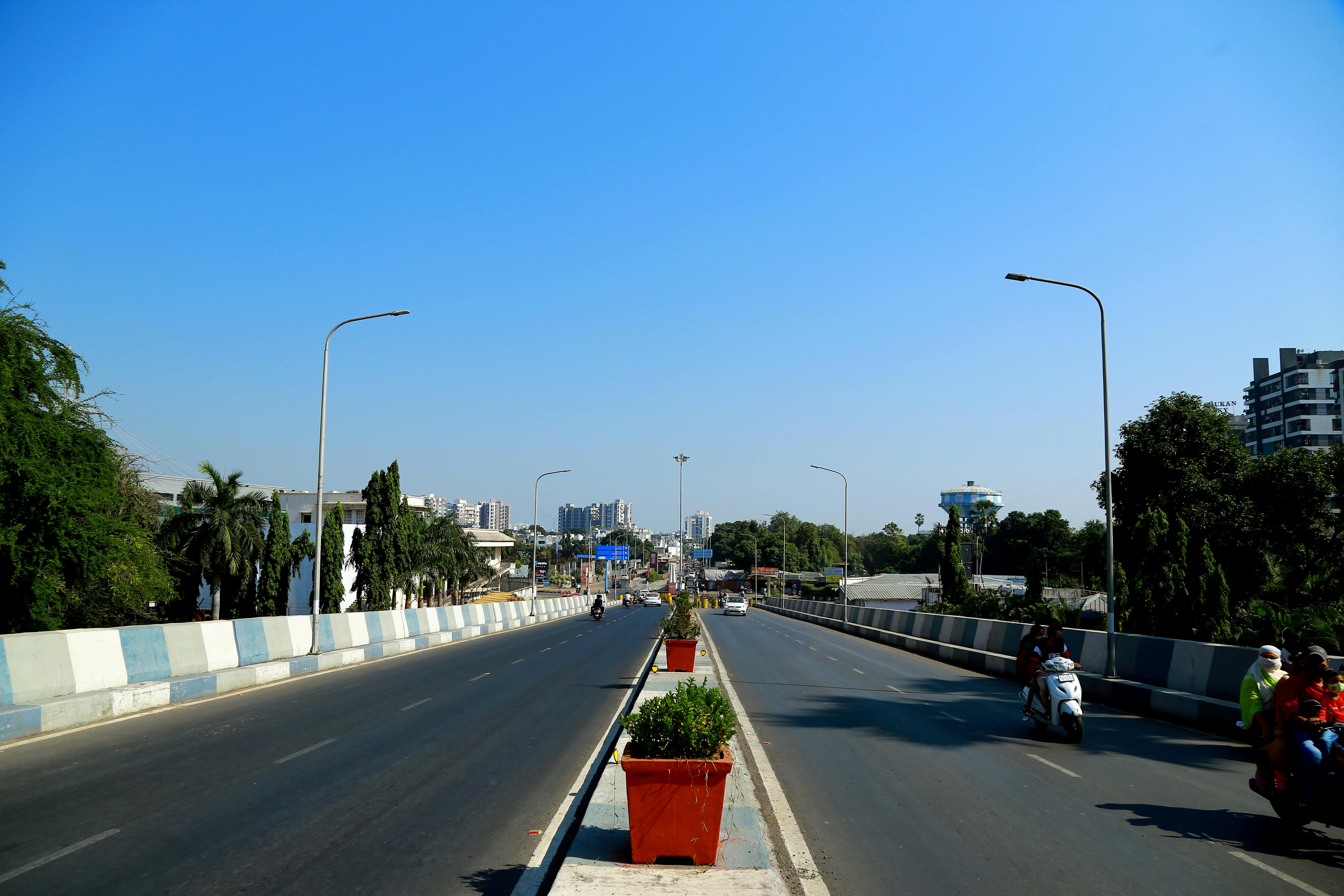An urban highway in Surat, India, showcasing city infrastructure and traffic under a clear blue sky. | Indian Village Development
