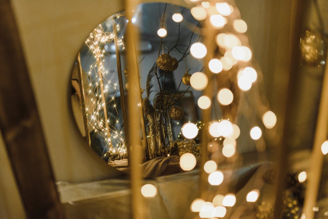 A Round Mirror with a Reflection of Christmas Decors on a Brown Wall 