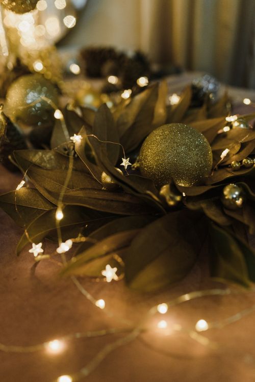 Free Close-up of Christmas baubles and lights on leafy decor, creating a warm holiday ambiance. Stock Photo