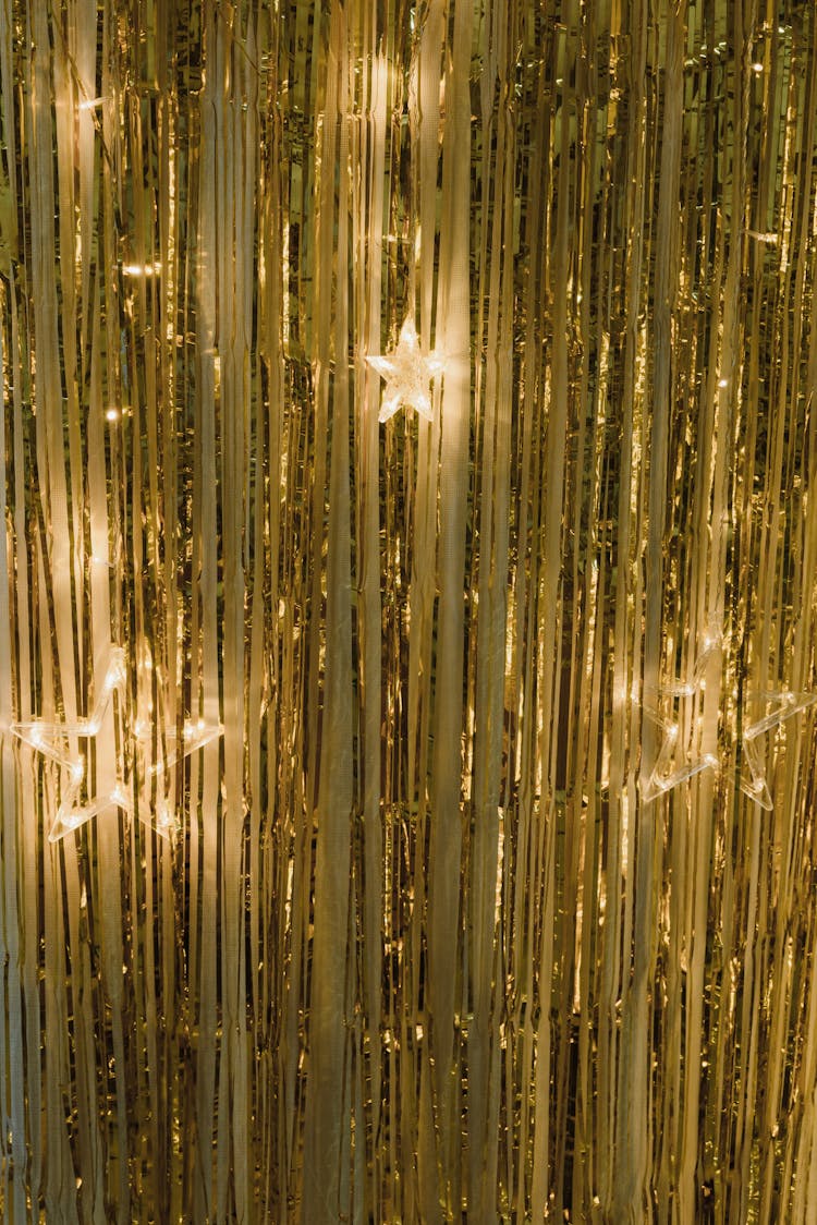 Star Shape Lights Hanging On A Gold Curtain At Christmas 