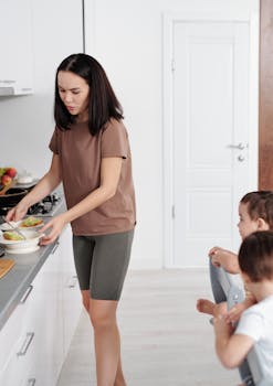 A mother serves food to two young boys in a modern kitchen setting.