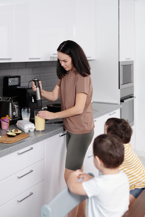 Free Woman Preparing Food for Children in a Kitchen  Stock Photo