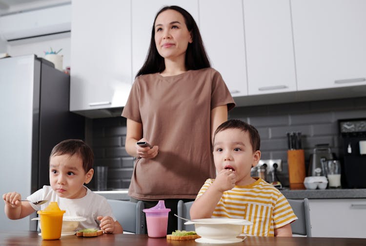 Mother With Sons In A Kitchen Watching TV