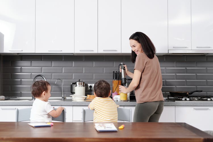 Mother Blending Food For Little Sons In The Kitchen 