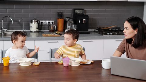 A mother and her two young boys enjoying breakfast together in a modern kitchen.