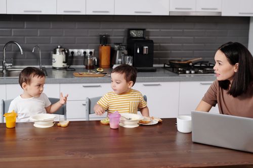 Free A mother and her two young boys enjoying breakfast together in a modern kitchen. Stock Photo