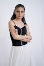 A Woman in Black Tank Top and White Skirt with Her Arms Crossed