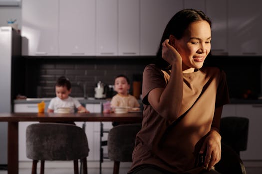 Smiling mother enjoying a moment at home while her children eat in a modern kitchen.