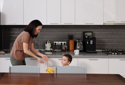 A mother and son engage in conversation in a contemporary kitchen setting