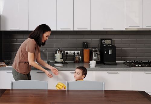 Free A mother and son engage in conversation in a contemporary kitchen setting. Stock Photo