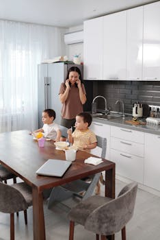 Mother multitasking with sons eating breakfast in a modern kitchen.