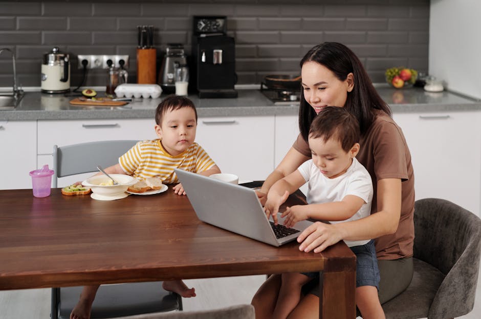 Does Baby-Led Weaning Help With First Foods? A mother with her two sons uses a laptop in the kitchen during breakfast time.
