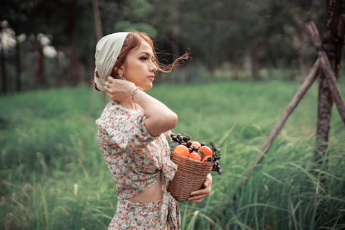 Charming country woman carrying basket with fruits