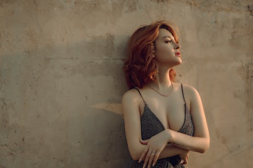 Dreamy woman leaning on shabby wall