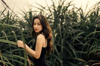 Asian lady standing in tall grass on green meadow