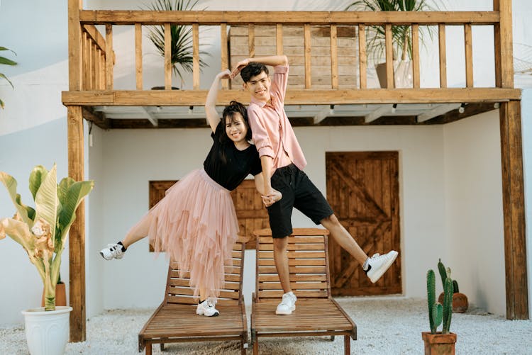 Couple On Deckchair In Street Making Heart Shape With Raised Arms