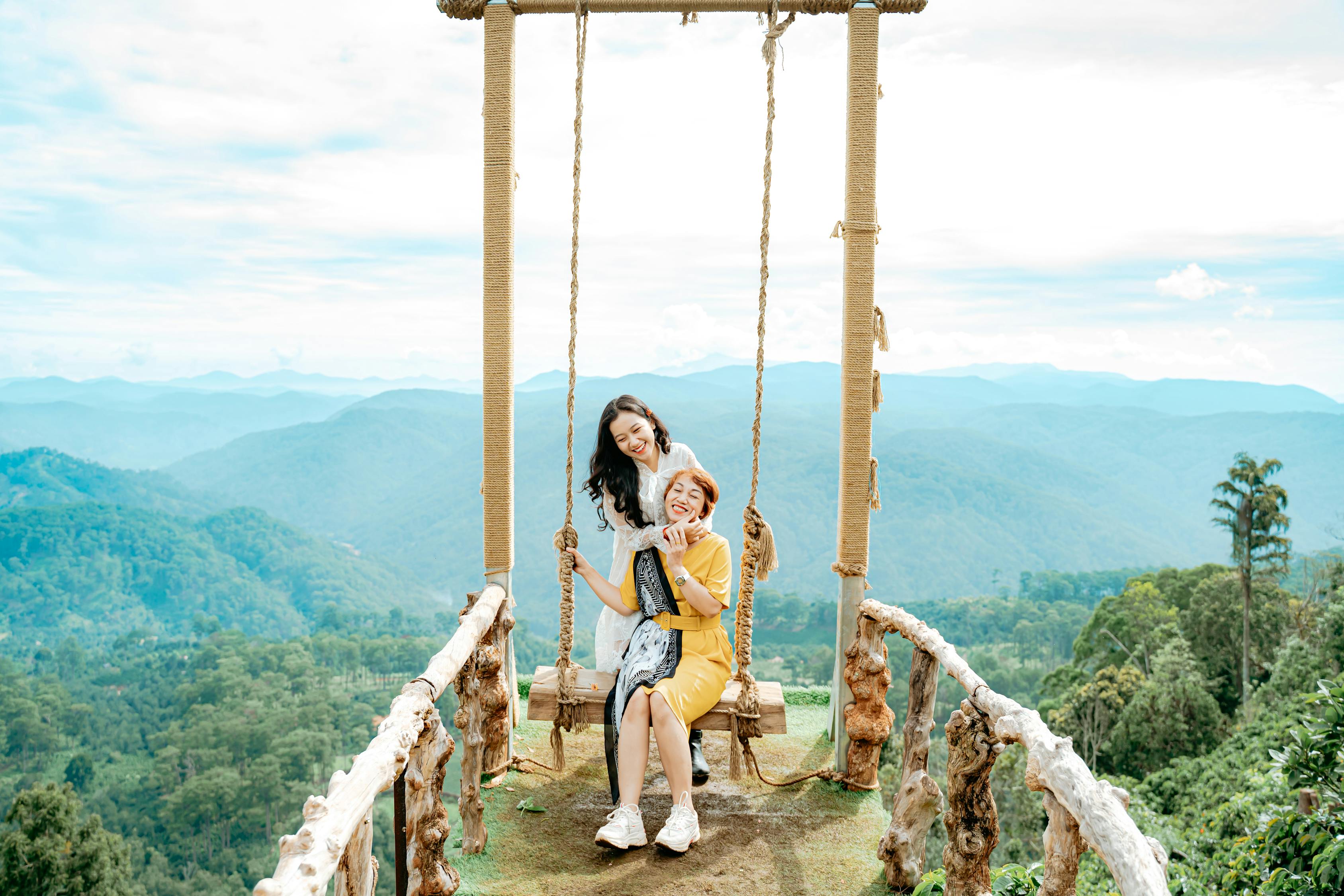 Content Asian mom with daughter on swing against green mounts · Free ...